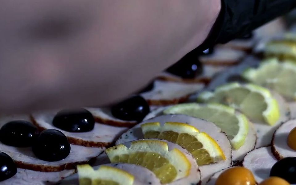 Kalte Platte mit Aufschnittröllchen, Zitronenspalten, schwarzen Oliven und Physalis